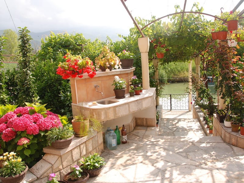 Summer kitchen in the garden of a house in Igalo, Montenegro: stone sink, blooming hydrangeas, and a view of the river from the terrace.