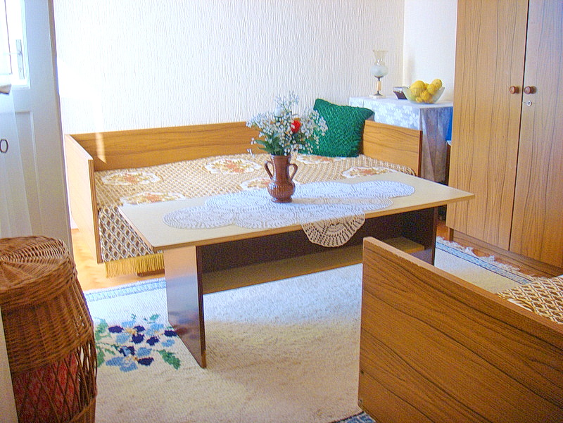 Living room interior in a house in Baošići, Montenegro: wooden furniture, a sofa with a throw, and a light-colored rug.