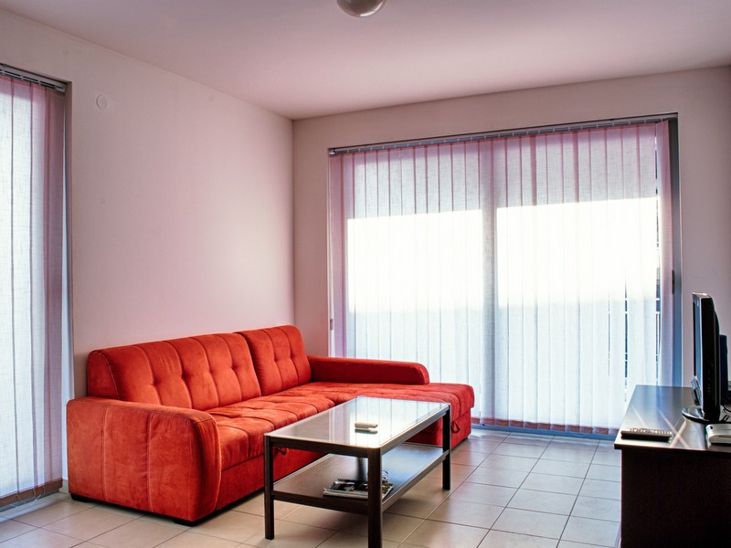 Bright living room with a red sofa and panoramic windows in an apartment in Petrovac, Montenegro.