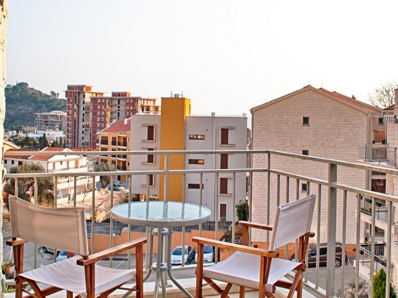 Balcony with furniture and city view in an apartment, Petrovac, Montenegro. Cozy outdoor seating area.