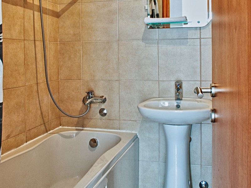 Bathroom in an apartment in Petrovac, Montenegro: white fixtures, a bathtub, and beige tile interior finish.
