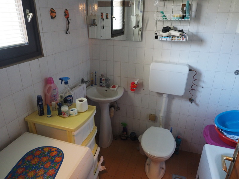 Bathroom in an apartment in Bar, Montenegro: white tile, fixtures, vanity, and mirror in a residential interior.