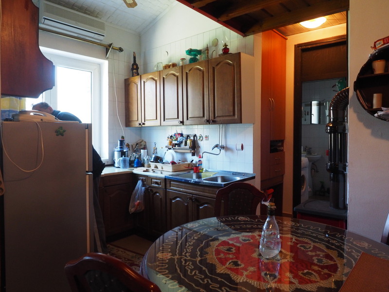 Cozy kitchen with wooden cabinets and a dining table in an apartment for sale, Bar, Montenegro.