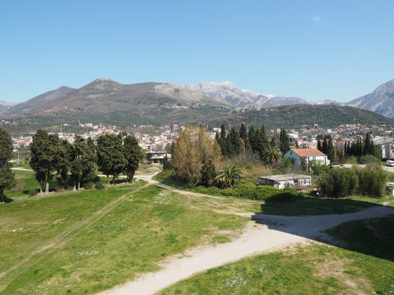 Panoramic view of the mountains and the city of Bar in Montenegro with green grounds and cypress trees near the residential complex.