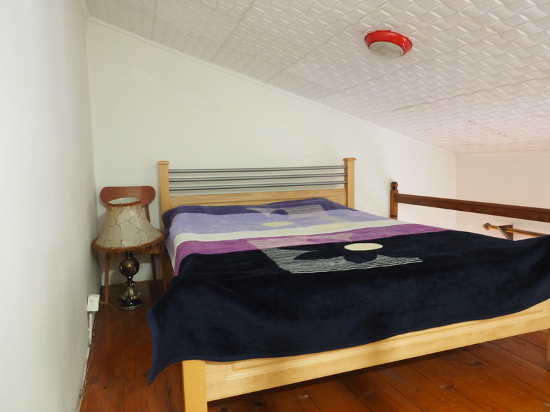 Attic bedroom in an apartment in Bar, Montenegro: double bed, wooden floor, and a cozy table lamp.
