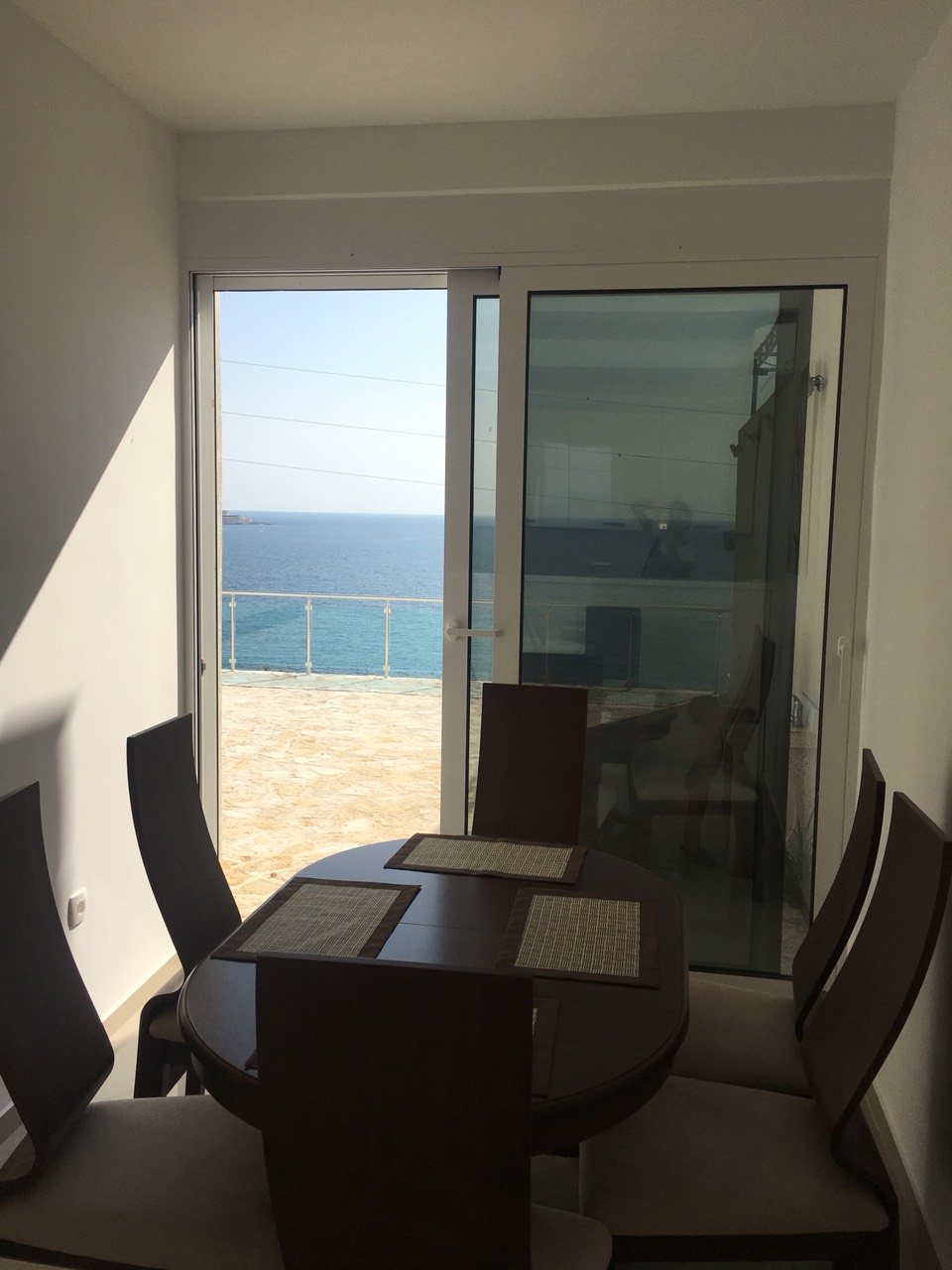 Dining area in a house on the Bar Riviera, Montenegro: a table with a sea and terrace view through panoramic doors.