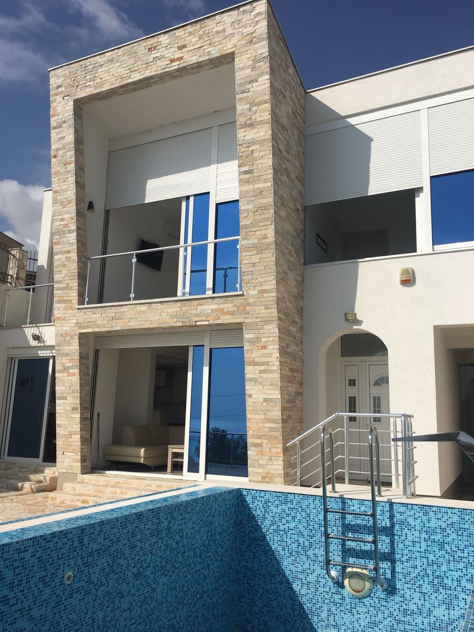 Modern villa with a pool and stone finish in Šušanj, Bar Riviera, Montenegro: view of the terraces and house facade.