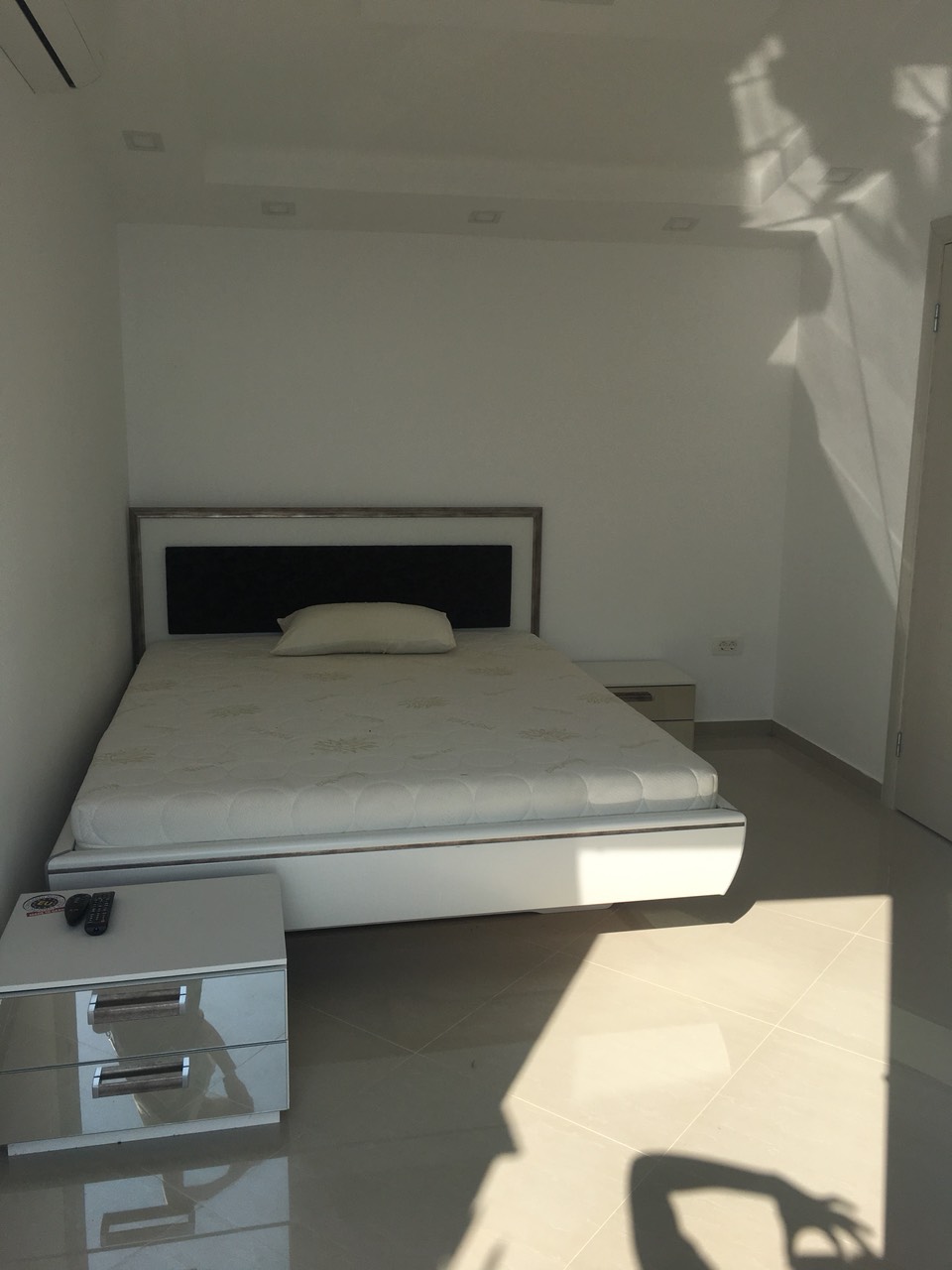 Modern bedroom with a double bed and glossy nightstands in the house, Barskaya Riviera, Montenegro.