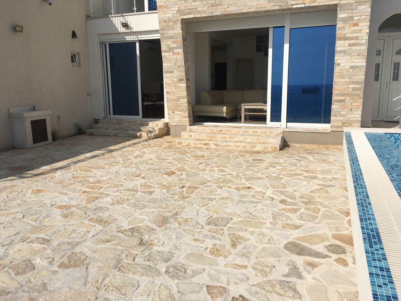 Terrace with a pool and sea view by the house in Shushan, Bar Riviera, Montenegro: stone finish and panoramic windows.