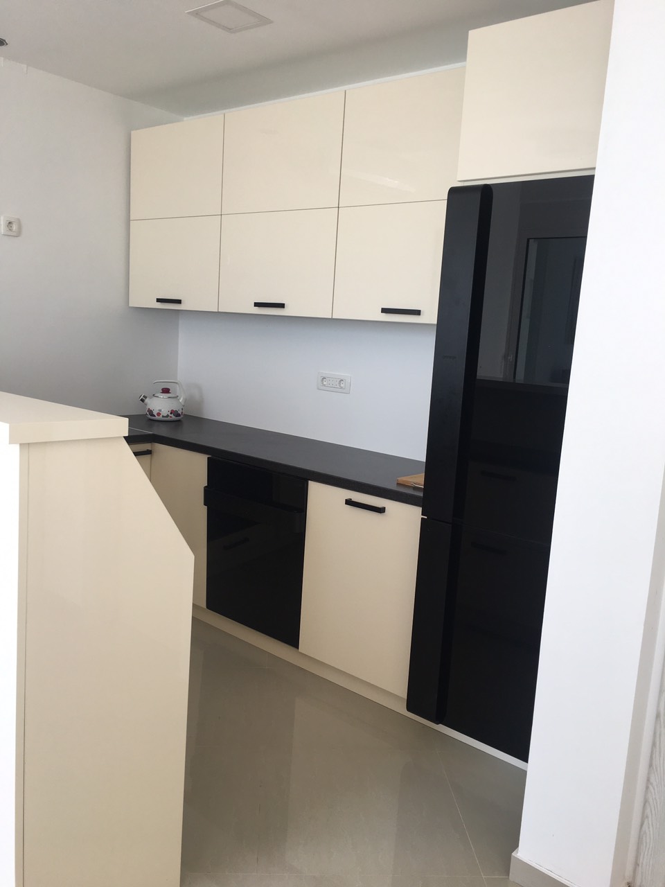 Modern kitchen in a house, Barska Riviera, Montenegro: white cabinets, black appliances and countertop, tiled floor.