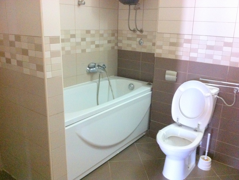Modern bathroom with a white bathtub and beige-toned tiles in an apartment, Herceg Novi, Montenegro.
