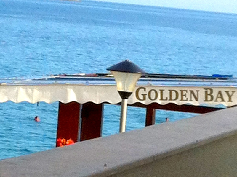 View from the balcony of the sea and Golden Bay beach in Herceg Novi, Montenegro: a panorama of the coastline and a street lamp.