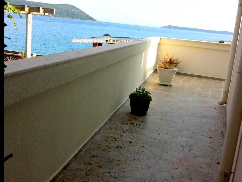 Spacious balcony with sea view in an apartment in Herceg Novi, Montenegro, with floor tiles and flower pots.
