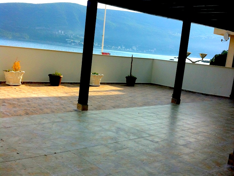 Spacious terrace with sea view in an apartment, Herceg Novi, Montenegro: tiled floor and decorative plants.