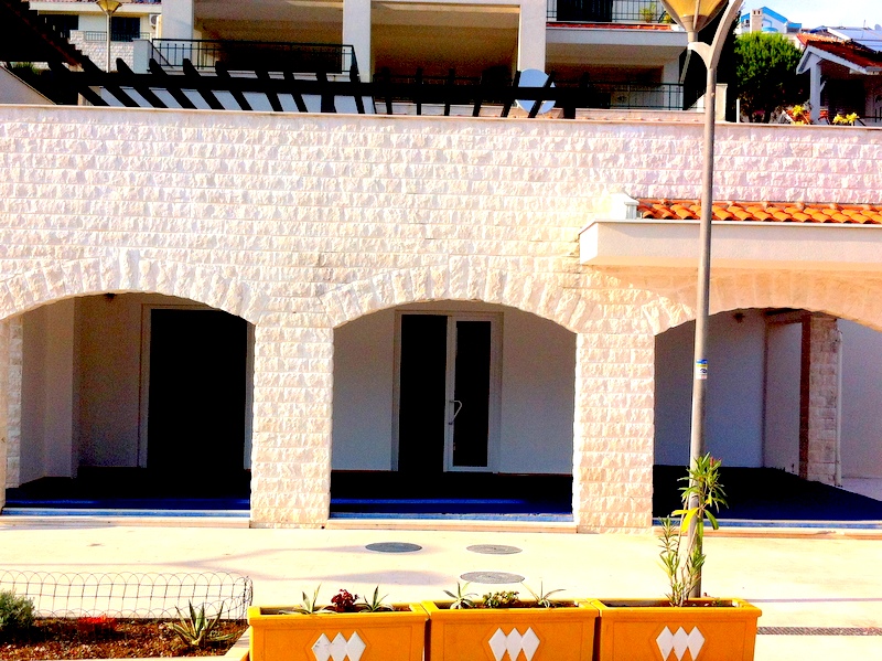Facade of a white stone house with arched terraces in Herceg Novi, Montenegro: street view of the residential complex.