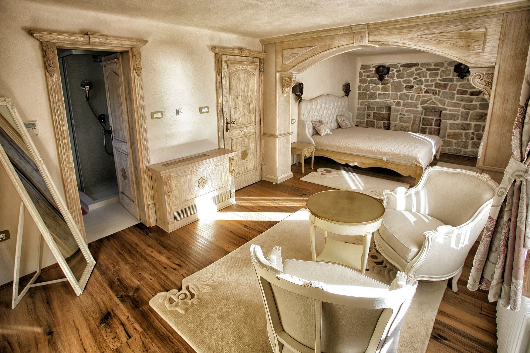 Bedroom in a villa in Reževići, Montenegro: stonework, wood finishes, a double bed, and a seating area.