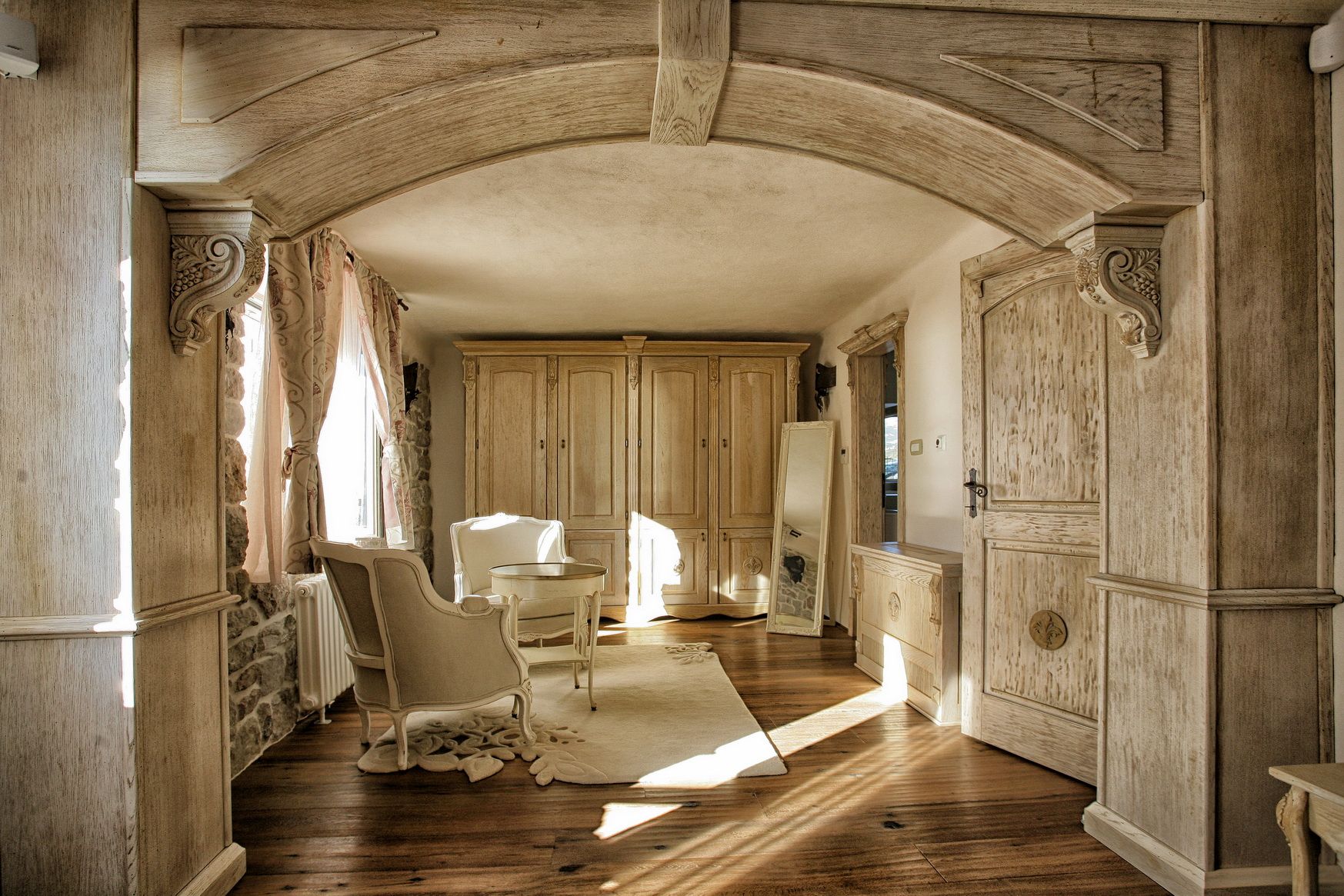 Villa living room in Reževići, Montenegro: interior with wood paneling, an arched opening, light-colored furniture, and parquet flooring.