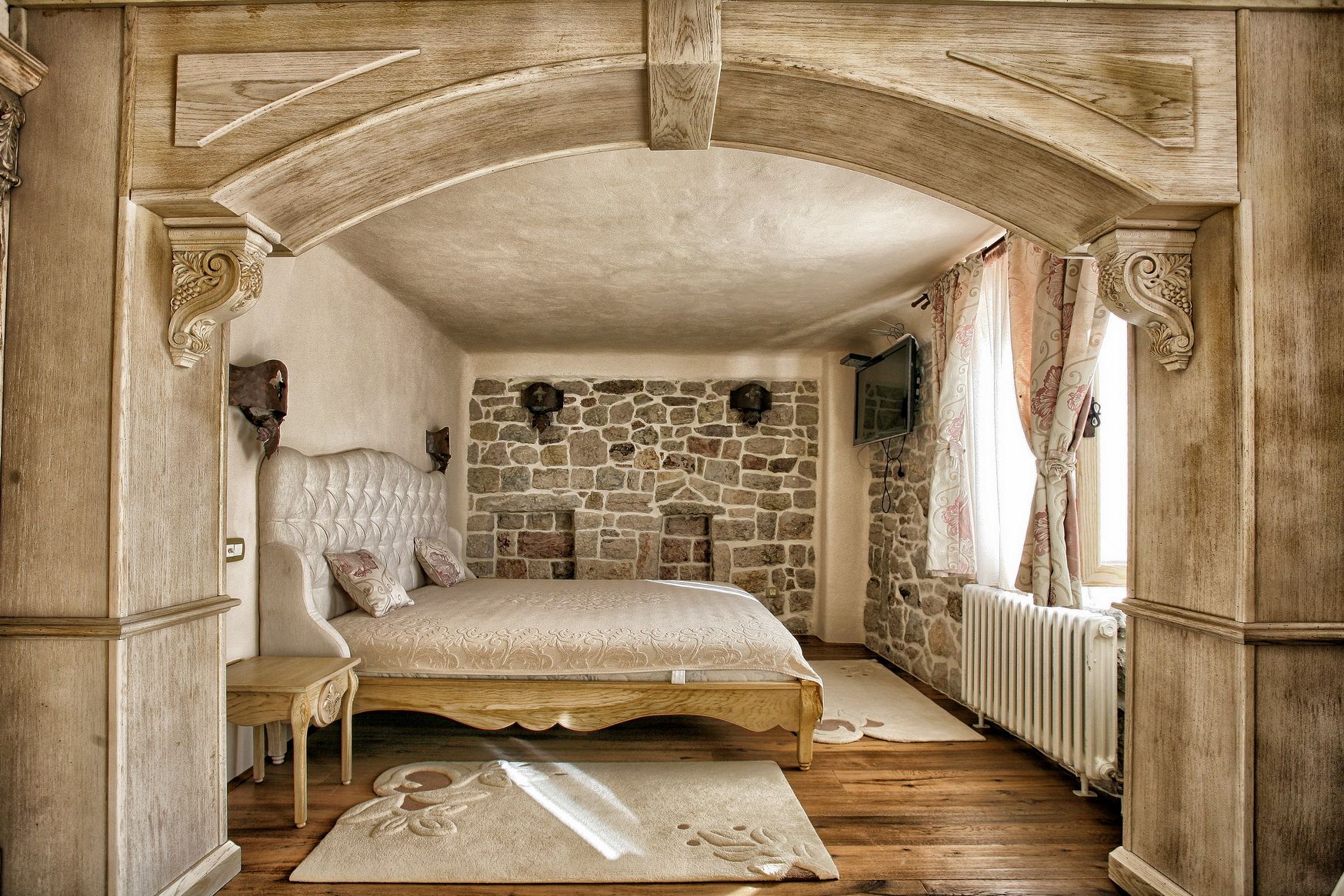 Bedroom in a villa in Reževići, Montenegro: stone masonry, wooden arch, double bed, and vintage interior.