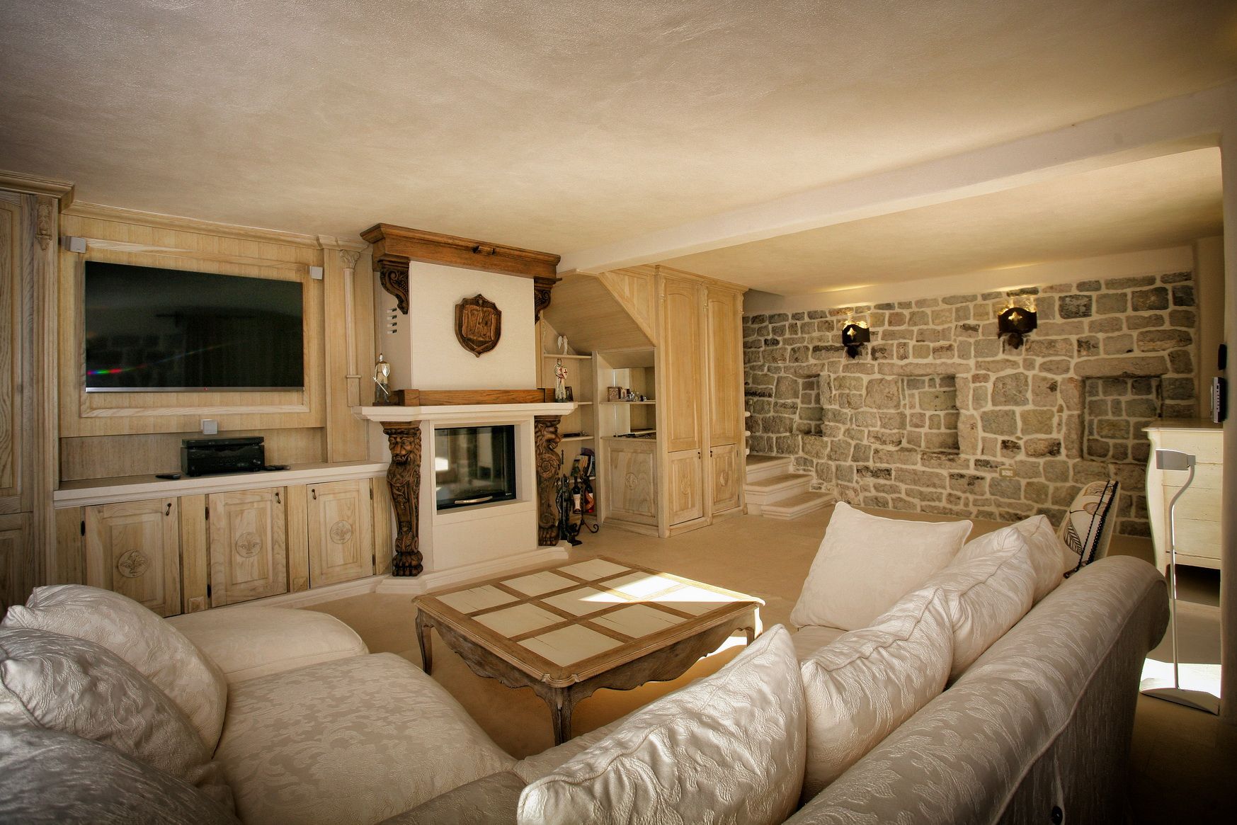 Villa living room in Reževići, Montenegro: interior with a fireplace, stone walls, and light rustic-style furniture.
