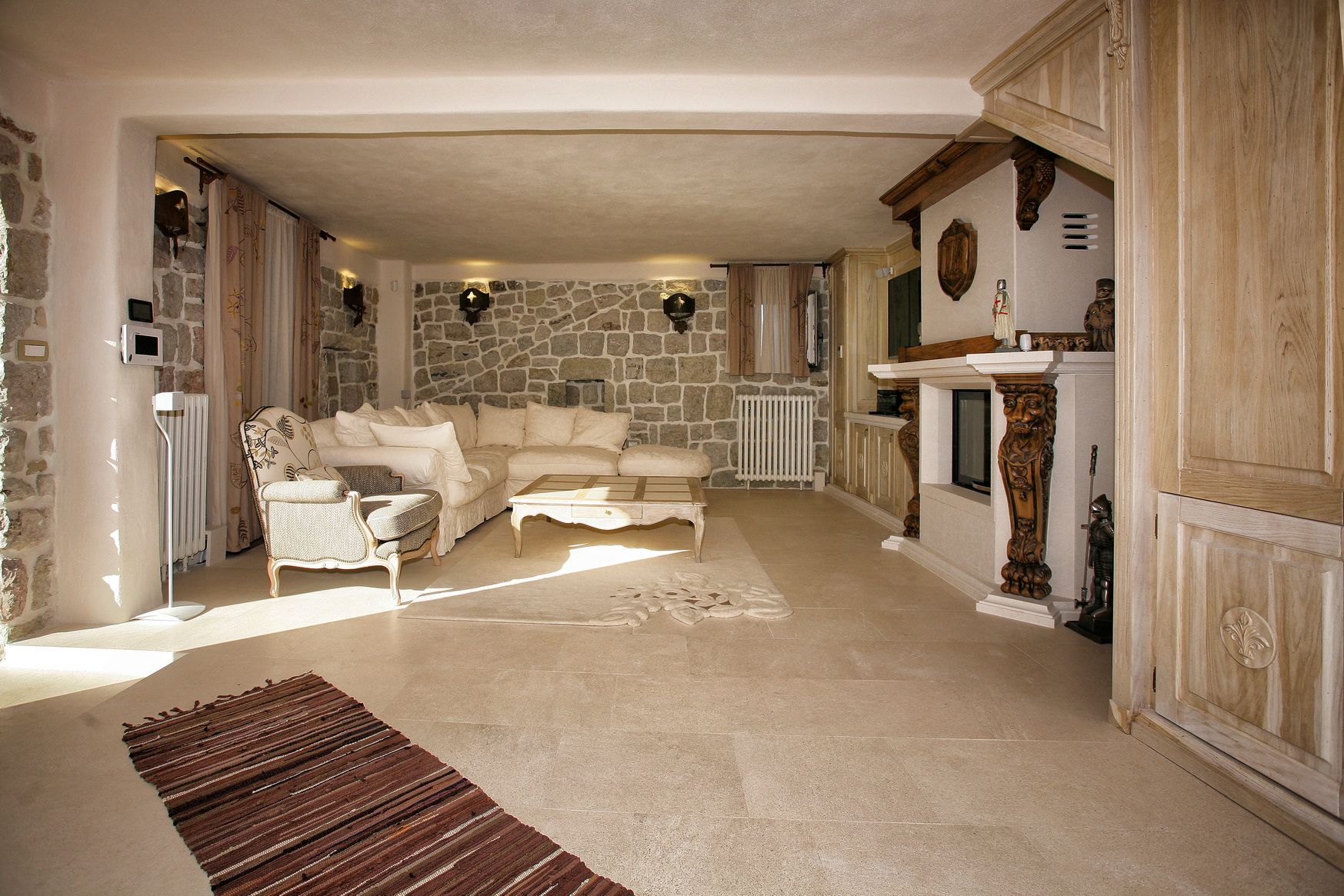 Villa living room in Reževići, Montenegro: stone walls, classic furniture, a fireplace with carved decor, and a bright interior.