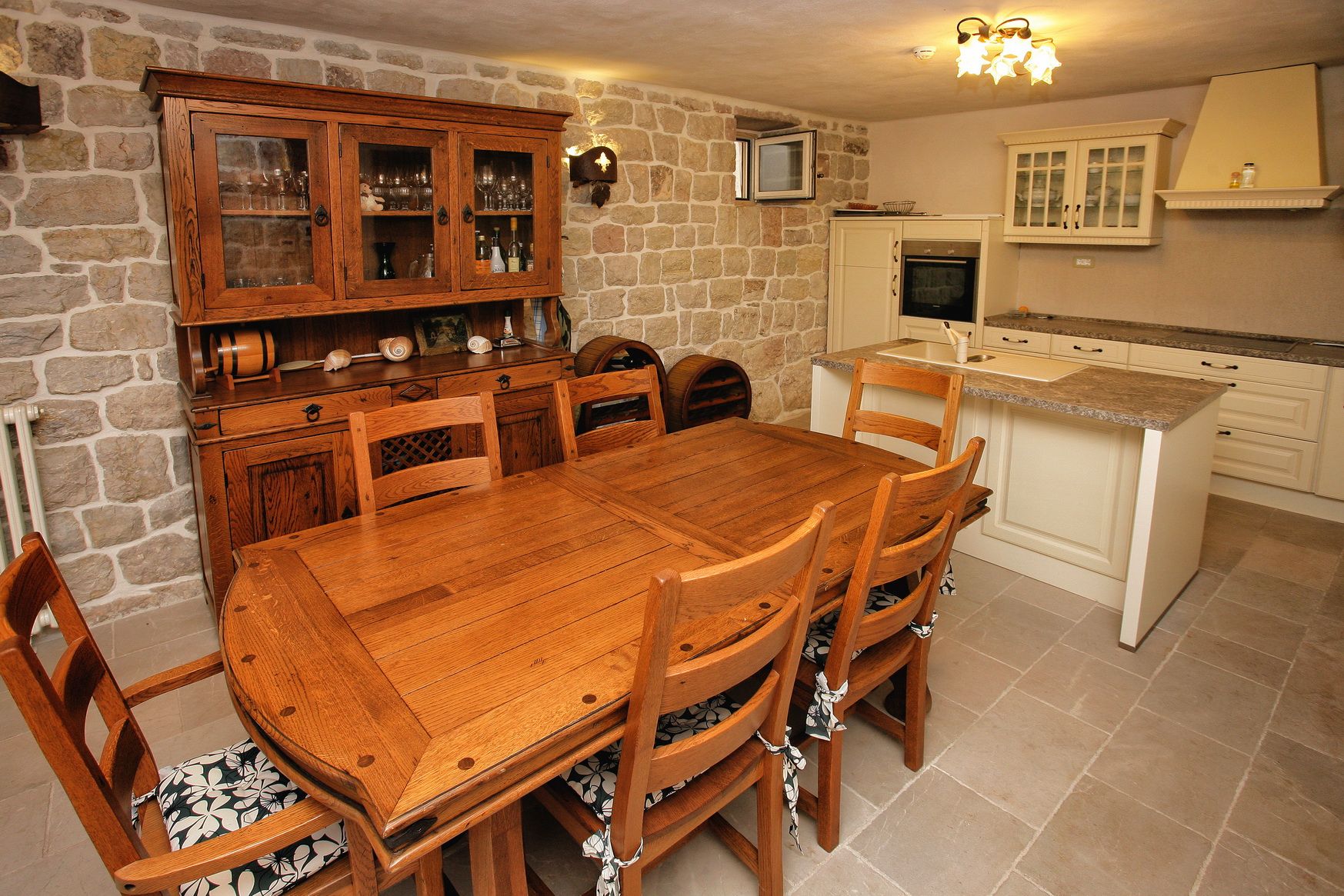 Kitchen-dining room with stone walls and wooden furniture in a villa in Reževići, Montenegro.