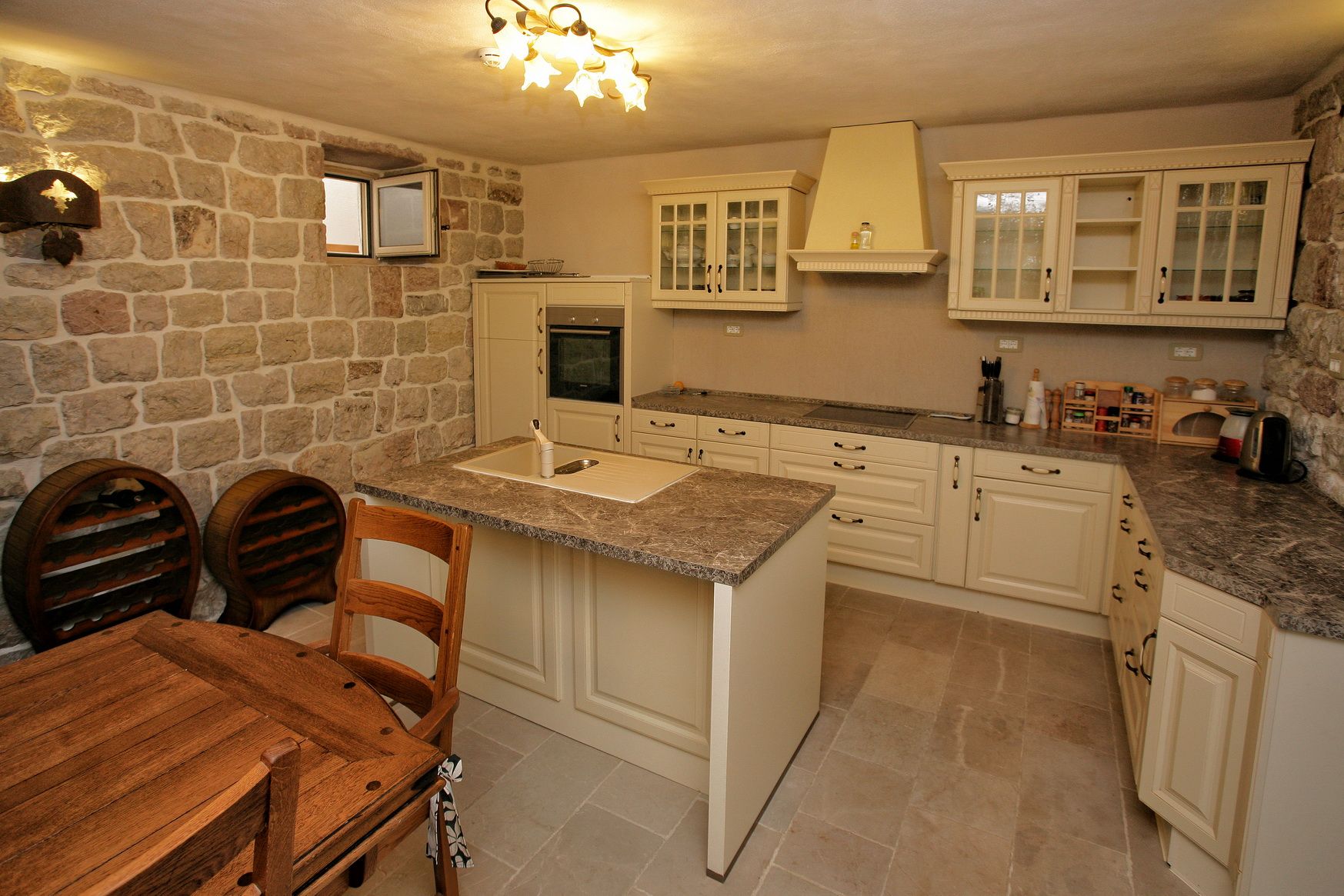 Rustic-style kitchen with stone walls and an island in a villa in Reževići, Montenegro: light furniture and wooden decor.