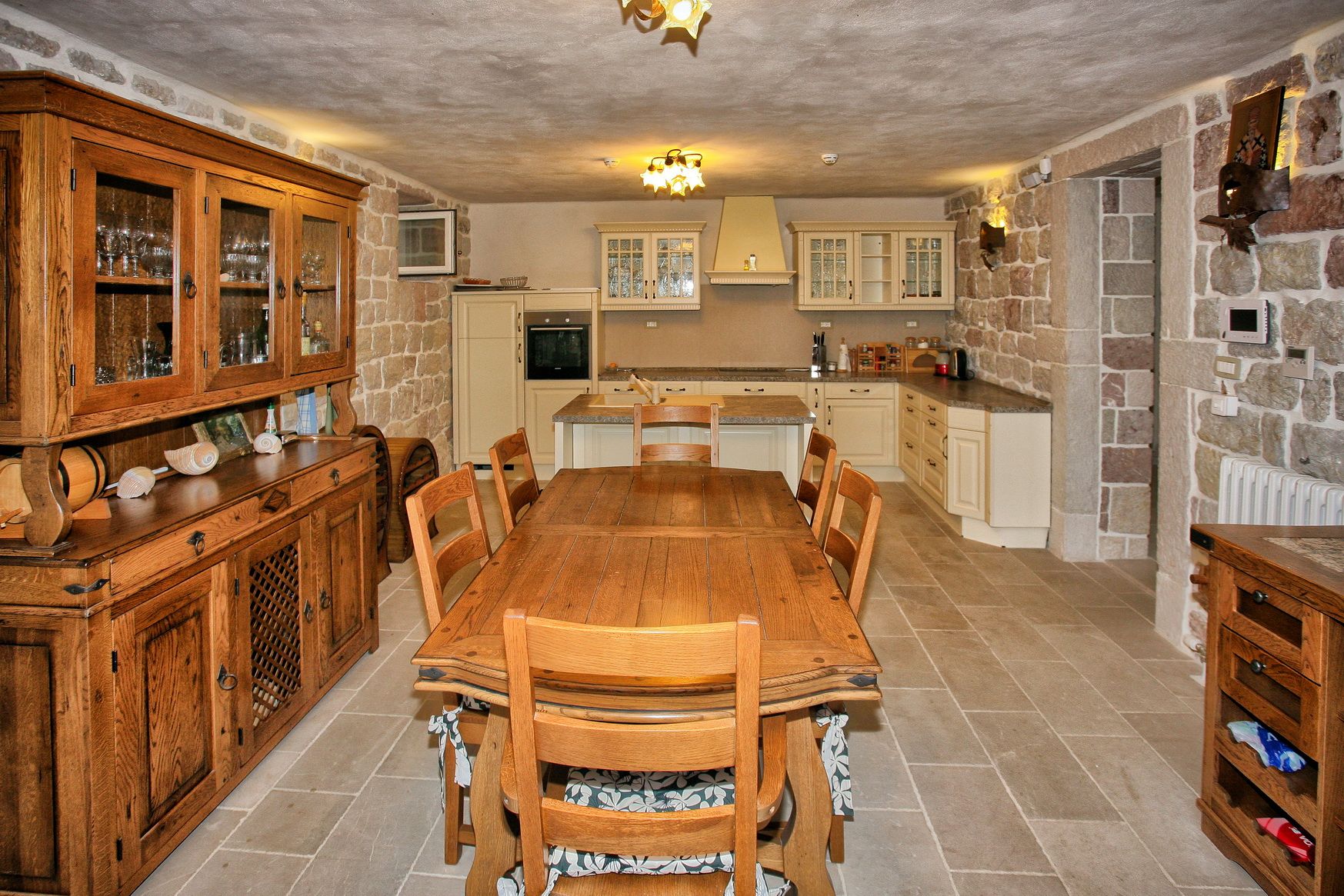 Kitchen-dining room with stone walls and wooden furniture in a villa in Reževići, Montenegro. Rustic-style interior.