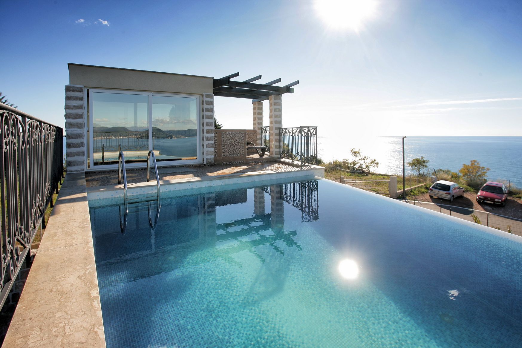 Infinity pool at a villa in Reževići, Montenegro, with panoramic sea views and a terrace with a pergola.