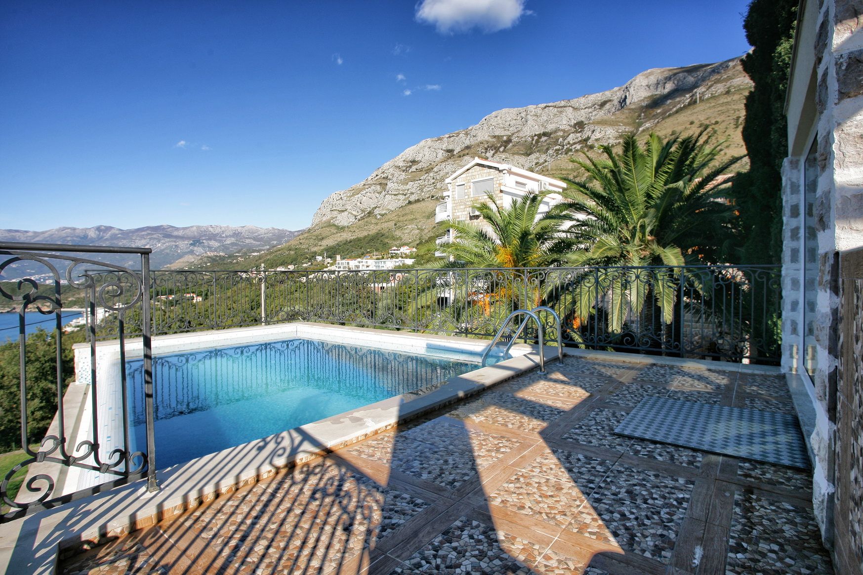 An outdoor pool on the villa terrace in Rezevici, Montenegro, with panoramic views of the mountains and the sea.