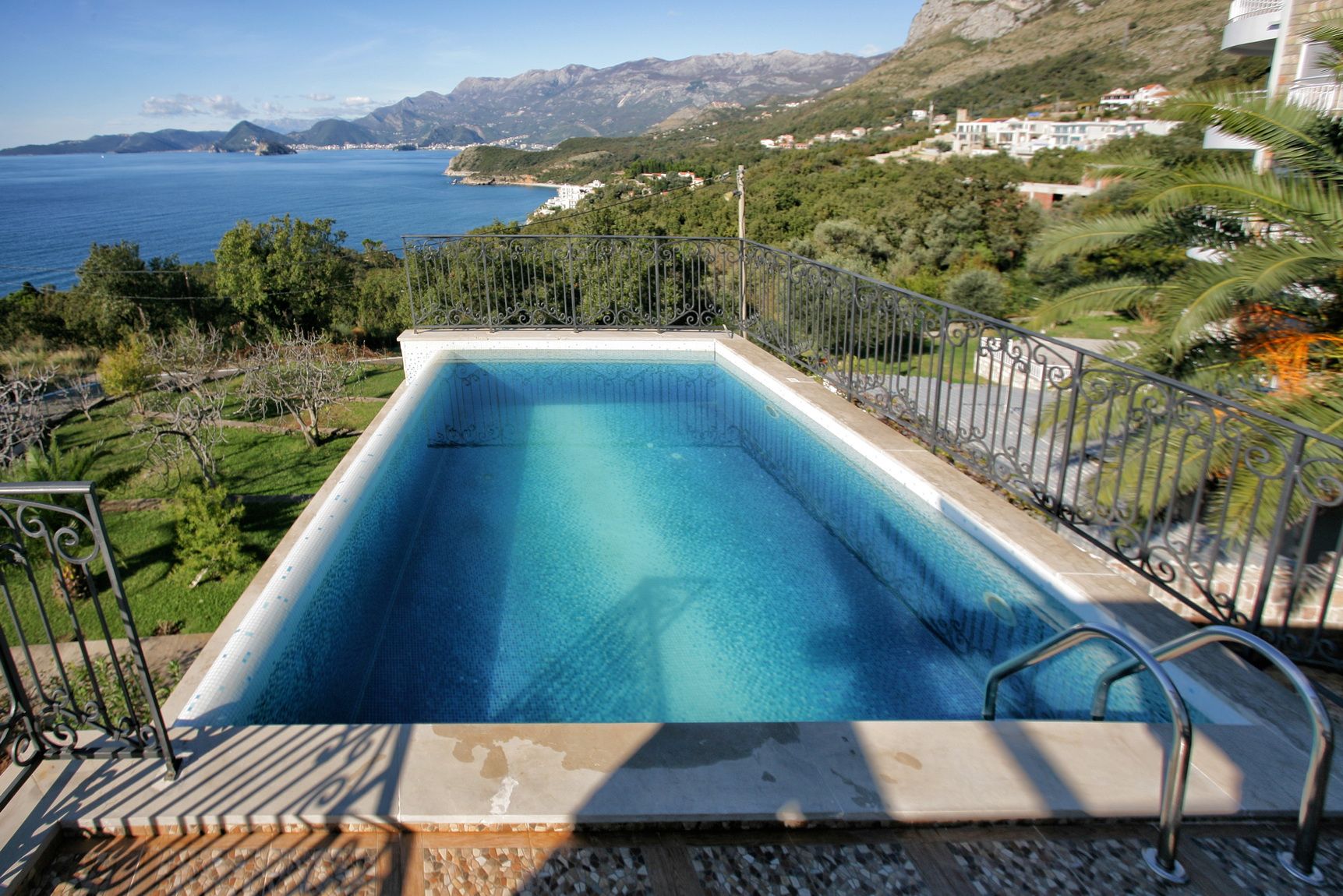 Outdoor pool at a villa in Reževići, Montenegro, with panoramic views of the Adriatic Sea and mountains.