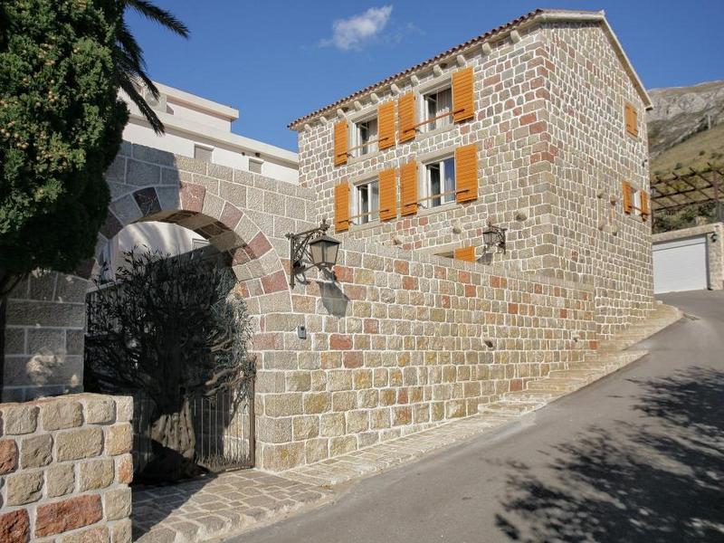 Three-story stone villa in traditional style with an arched entrance in Reževići, Montenegro.