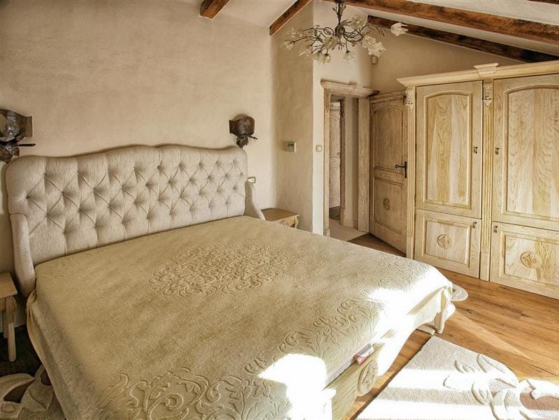 Bedroom in a villa in Rezevici, Montenegro: a double bed with a padded headboard, a wooden wardrobe, and a beamed ceiling.