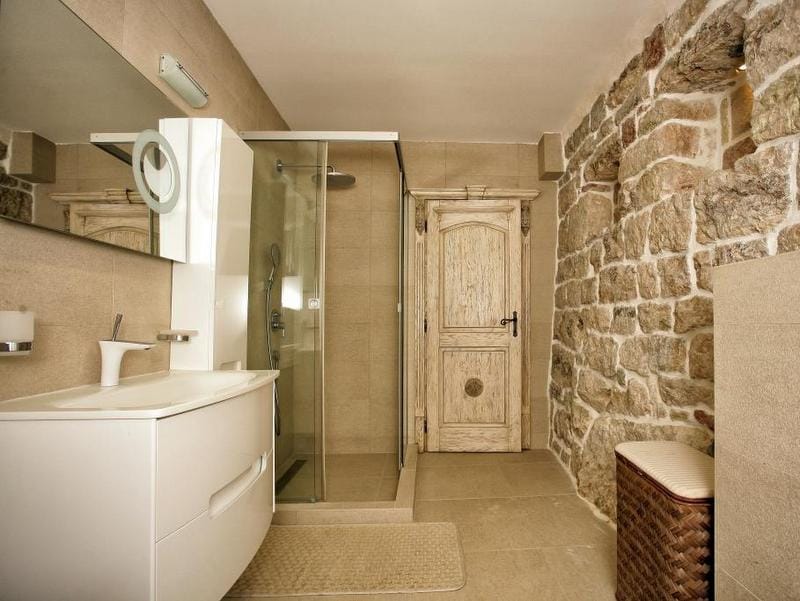 Bathroom in a villa in Reževići, Montenegro: modern shower cabin, stone finishes, and a stylish wooden door.