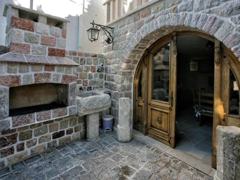 Stone terrace with barbecue and arched door at a villa in Reževići, Montenegro: a cozy Mediterranean-style relaxation area