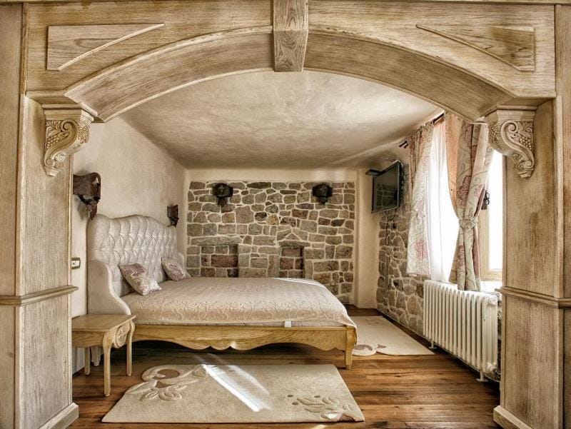 Rustic-style bedroom in a villa in Reževići, Montenegro: stone masonry, a wooden arch, and a double bed.