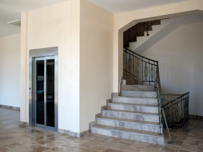 Entrance hall featuring a marble staircase and a glass elevator door.