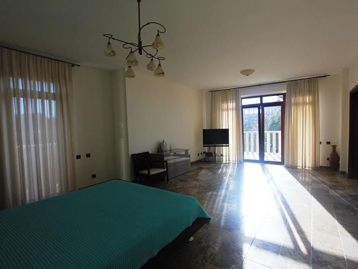Spacious bedroom in a villa in Petrovac, Montenegro: bed, marble floor, panoramic windows, and access to the terrace.