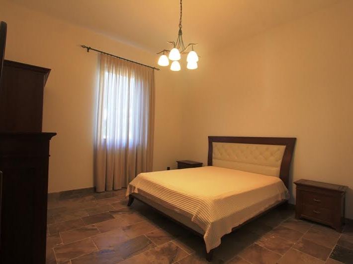 Cozy bedroom with a double bed and stone floor in a villa in Petrovac, Montenegro.
