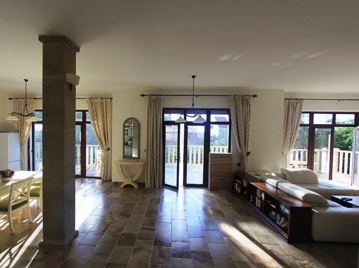 Spacious living room with stone flooring and access to the terrace in a villa in Petrovac, Montenegro. Modern furniture and decor.