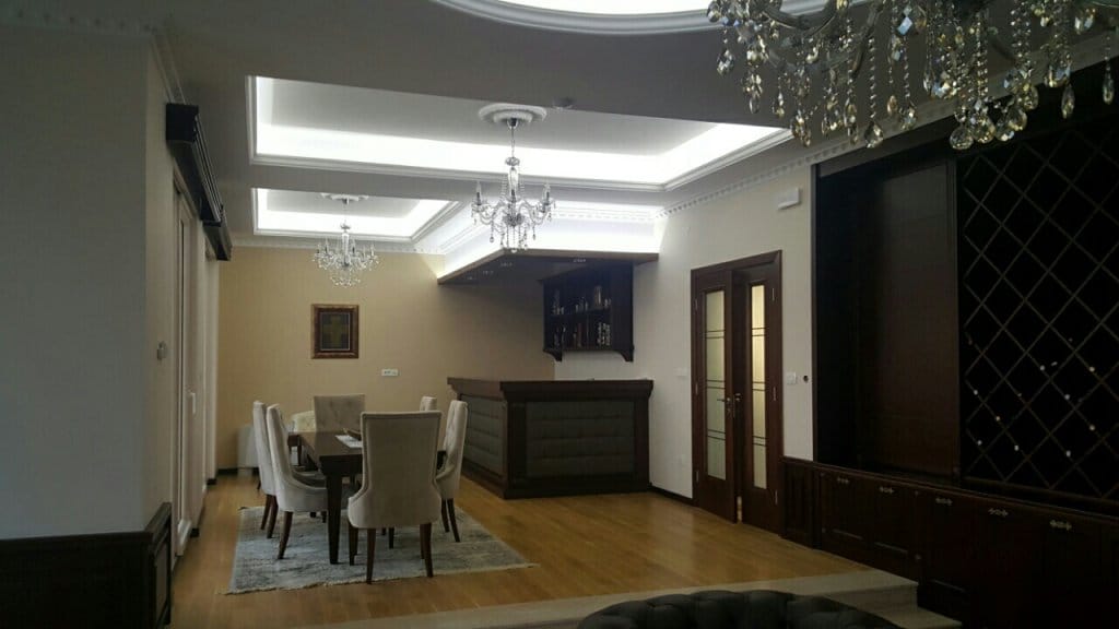 Living room with a bar counter and dining area in a villa in Reževići, Montenegro: classic interior with chandeliers.