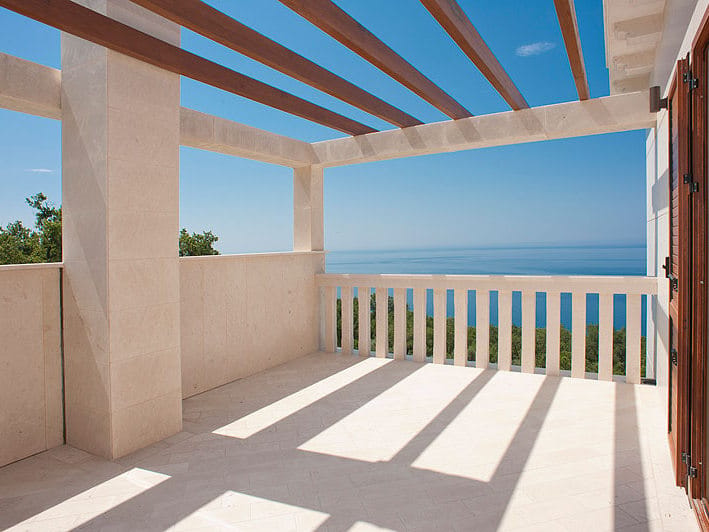Spacious villa terrace in Reževići, Montenegro, with stone finishes, a wooden pergola, and panoramic sea views.