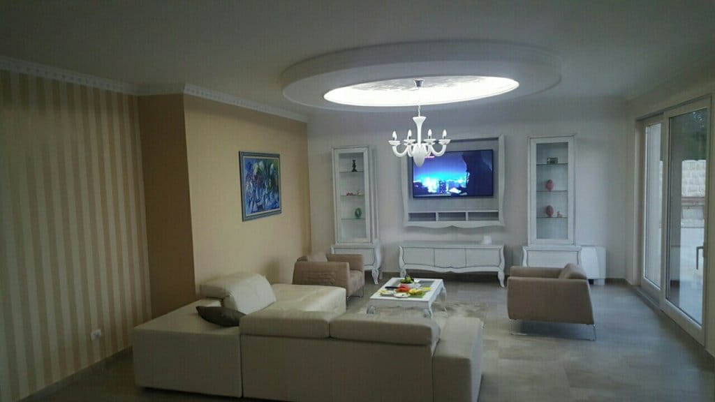 Spacious living room with white furniture and a designer ceiling in a villa in Reževići, Montenegro.