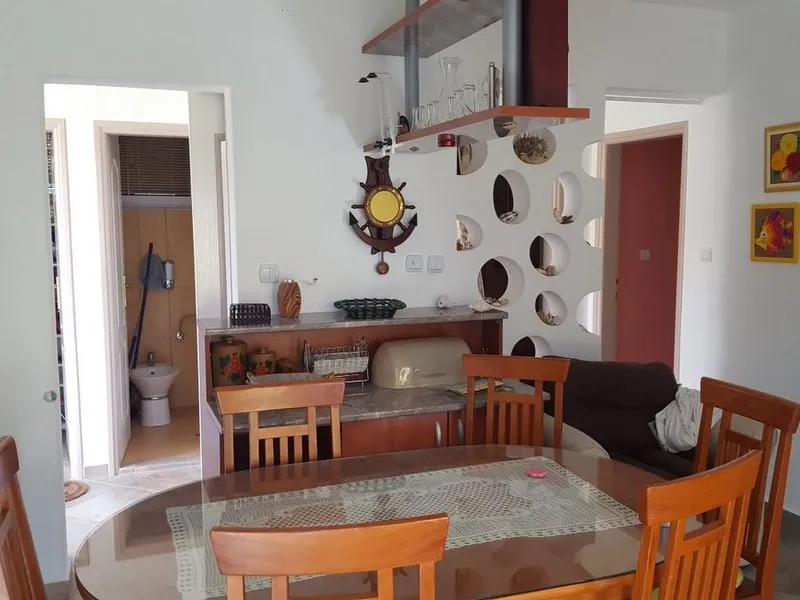 Dining area with wooden table and chairs, partial sofa view, and decorative partition wall with circular cutouts.
