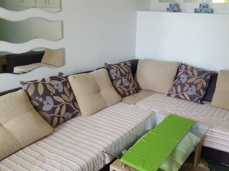 Corner sofa with decorative pillows and a glass coffee table in the living room of a house in Krymovice, Montenegro.