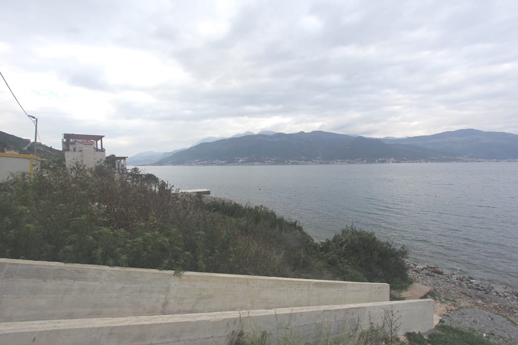 Sea and mountain view from a land plot in Krašići, Montenegro: coastline, concrete structures, and nature.
