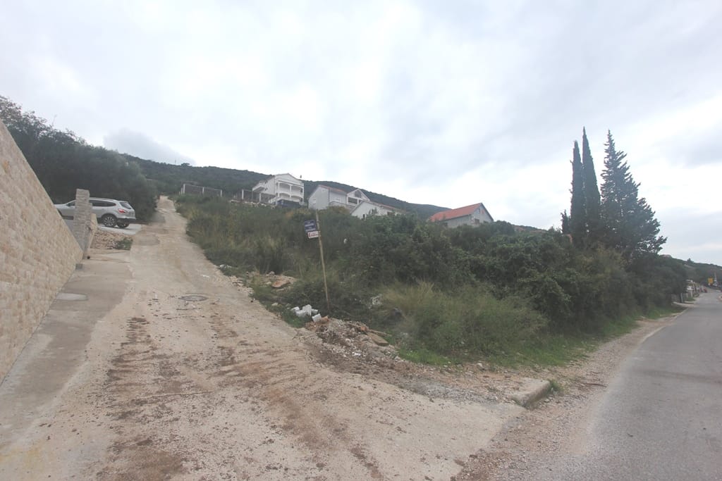 Building plot in Krašići, Montenegro: view of the access road, hilly terrain, and surrounding houses.