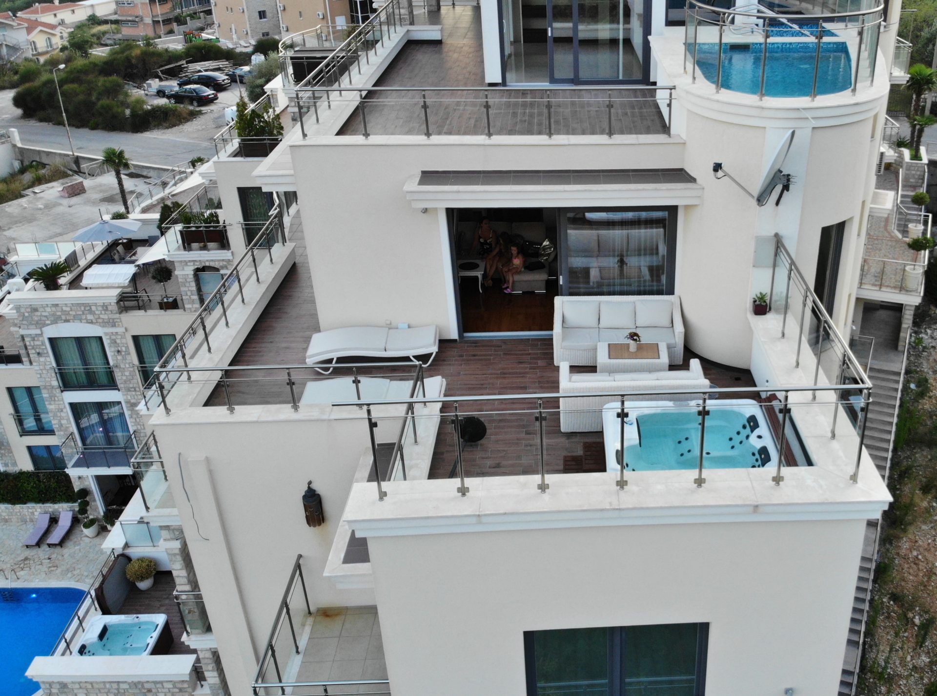 Penthouse terrace in Bečići, Montenegro: jacuzzi, wicker furniture, sun loungers, and panoramic sea and mountain views.