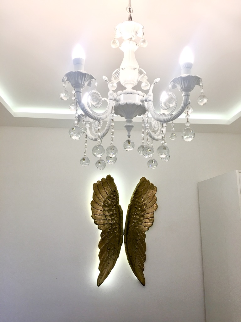 White crystal chandelier and gold wing decor in the interior of an apartment in Bečići, Montenegro.