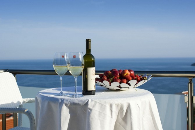 View from the penthouse balcony in Bečići, Montenegro: a table with wine and fruit against a panoramic view of the Adriatic Sea.