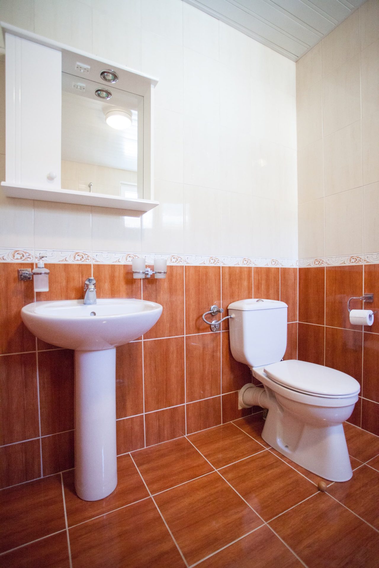 Bright bathroom in a penthouse, Becici, Montenegro: white fixtures, walls finished with terracotta tiles.